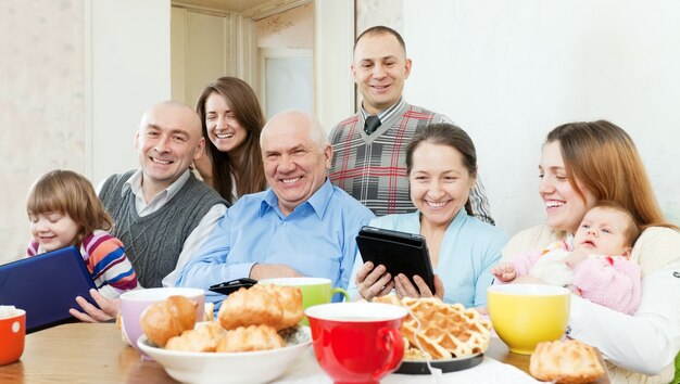 Familia feliz de tres generaciones con dispositivos electrónicos
