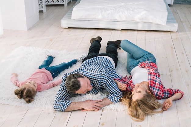 Familia feliz tumbado en la alfombra de piel en casa