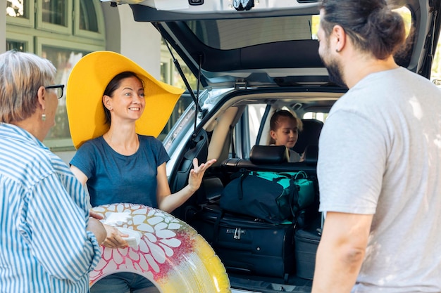 Foto gratuita familia feliz viajando de vacaciones junto al mar, saliendo con maleta y equipaje en el maletero del auto. niña, padres y abuelos que van al destino marítimo con automóvil, para viajar de vacaciones.