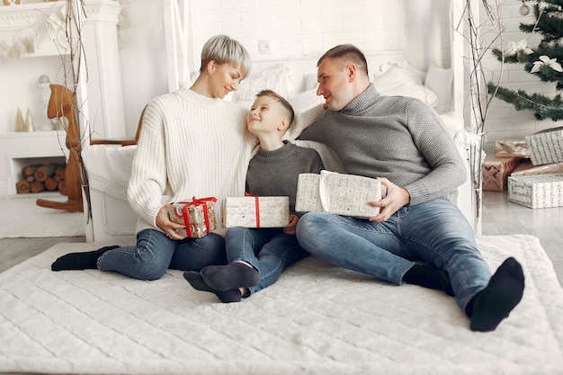 Foto gratuita familia en una habitación. niño cerca de la decoración navideña. madre con padre con hijo