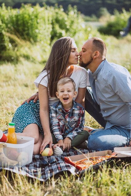 Familia haciendo un picnic y comiendo pizza en el parque