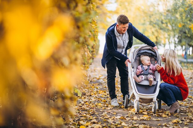 Familia con hija bebé caminando en un parque de otoño
