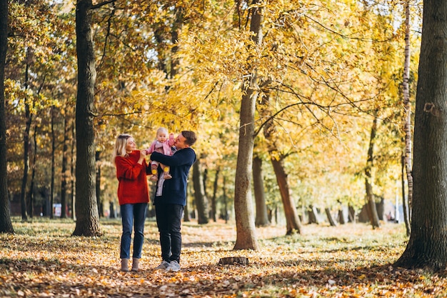 Familia con hija bebé caminando en un parque de otoño