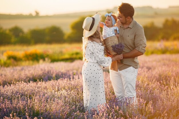 Familia con hija pequeña en campo lavanda. Mujer hermosa y lindo bebé jugando en el campo del prado. Vacaciones familiares en verano.