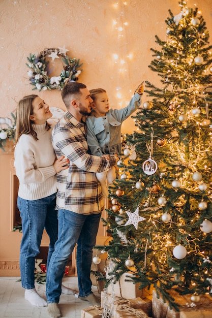 Familia con hija pequeña junto al árbol de navidad