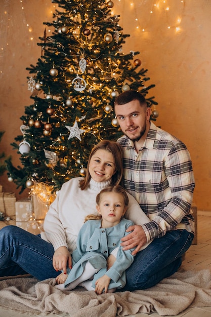 Familia con hija pequeña junto al árbol de navidad