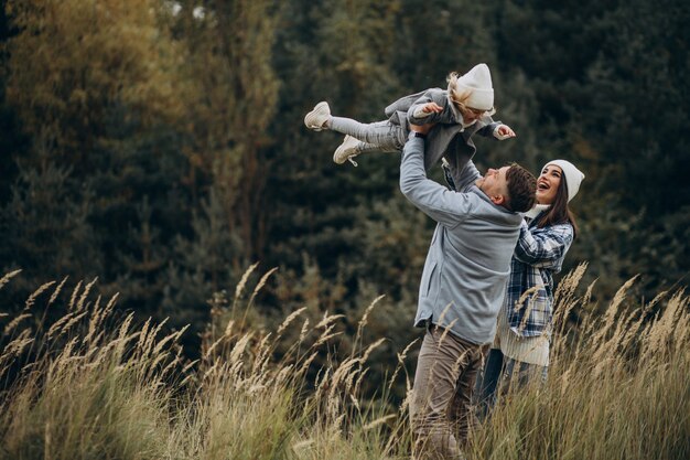 Familia con hija pequeña juntos en clima otoñal divirtiéndose