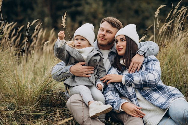 Familia con hija pequeña juntos en clima otoñal divirtiéndose