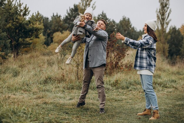 Familia con hija pequeña juntos en clima otoñal divirtiéndose