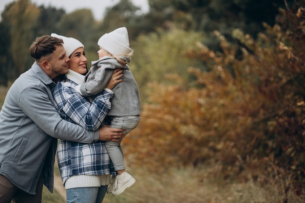 Foto gratuita familia con hija pequeña juntos en clima otoñal divirtiéndose