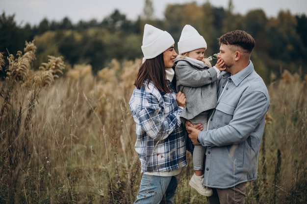 Familia con hija pequeña juntos en clima otoñal divirtiéndose