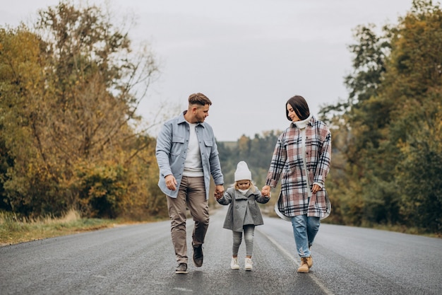 Familia con hija pequeña juntos en clima otoñal divirtiéndose