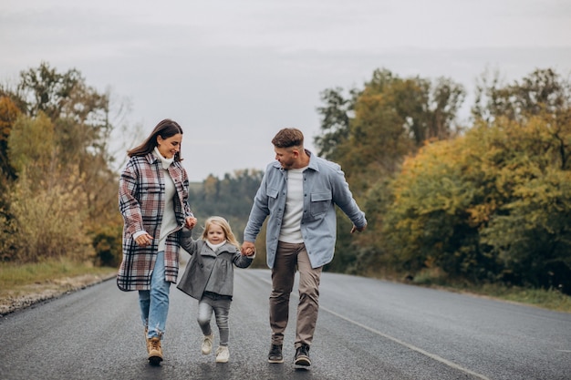 Familia con hija pequeña juntos en clima otoñal divirtiéndose