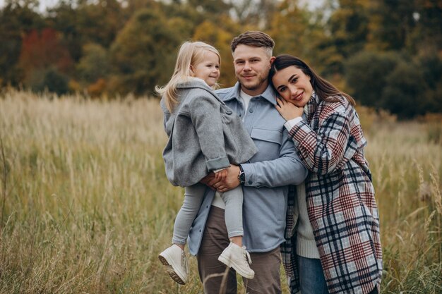 Familia con hija pequeña juntos en clima otoñal divirtiéndose