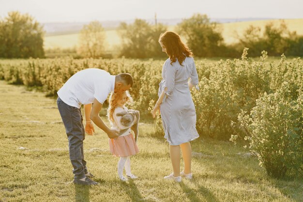 Familia con hija pequeña pasar tiempo juntos en campo soleado