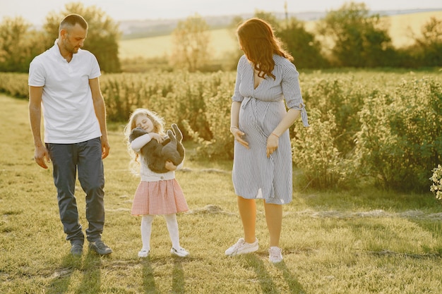 Familia con hija pequeña pasar tiempo juntos en campo soleado