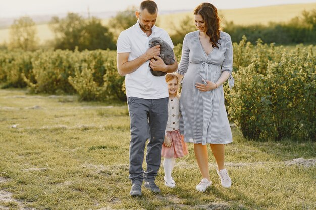 Familia con hija pequeña pasar tiempo juntos en campo soleado