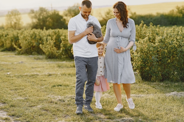 Familia con hija pequeña pasar tiempo juntos en campo soleado