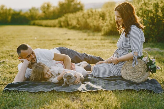 Familia con hija pequeña pasar tiempo juntos en campo soleado