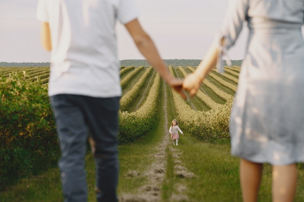 Familia con hija pequeña pasar tiempo juntos en campo soleado