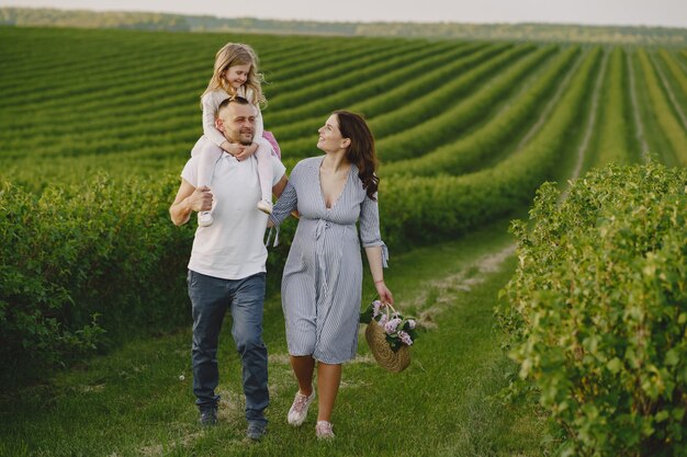 Familia con hija pequeña pasar tiempo juntos en campo soleado