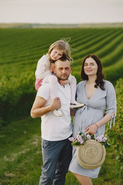 Familia con hija pequeña pasar tiempo juntos en campo soleado