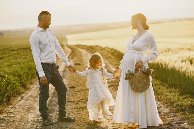 Familia con hija pequeña pasar tiempo juntos en campo soleado