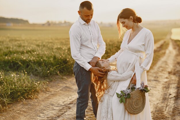 Familia con hija pequeña pasar tiempo juntos en campo soleado