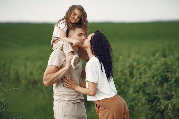 Familia con hija pequeña pasar tiempo juntos en campo soleado