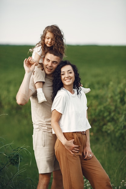 Familia con hija pequeña pasar tiempo juntos en campo soleado