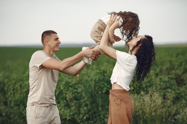 Familia con hija pequeña pasar tiempo juntos en campo soleado