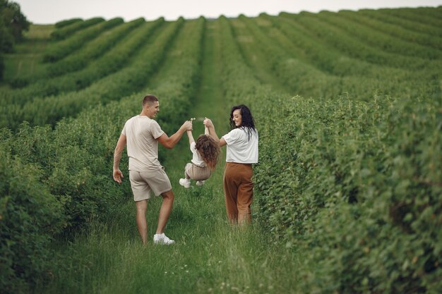 Familia con hija pequeña pasar tiempo juntos en campo soleado