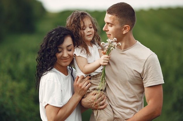 Familia con hija pequeña pasar tiempo juntos en campo soleado