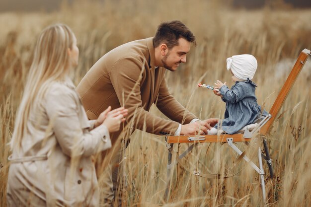 Familia con hija pequeña pintando en un campo de otoño