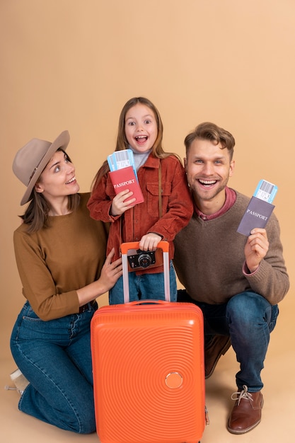 Familia con hija sosteniendo pasaportes y equipaje listo para viajar