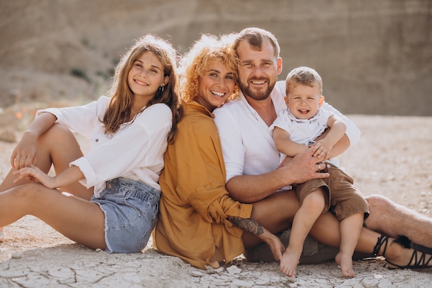 Familia con hijo e hija sentados en la arena