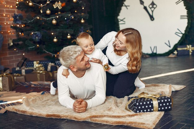 Familia con hijo pequeño en casa cerca del árbol de Navidad