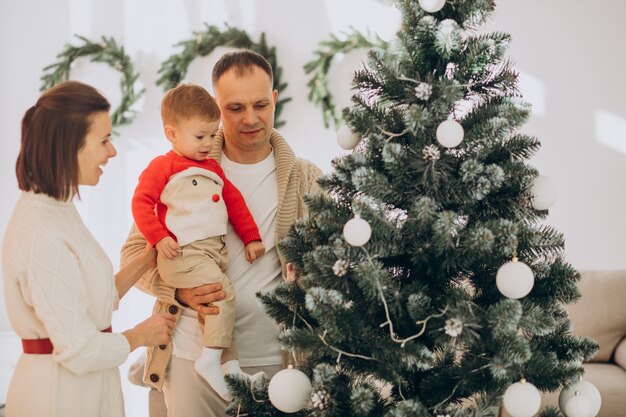 Familia con hijo pequeño en Navidad por árbol de Navidad en casa