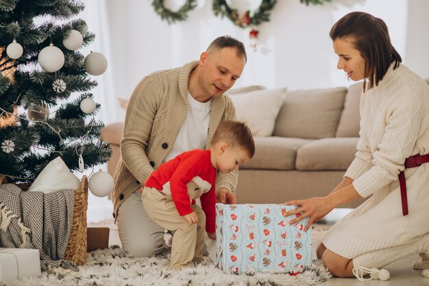 Familia con hijo pequeño en Navidad por árbol de Navidad en casa