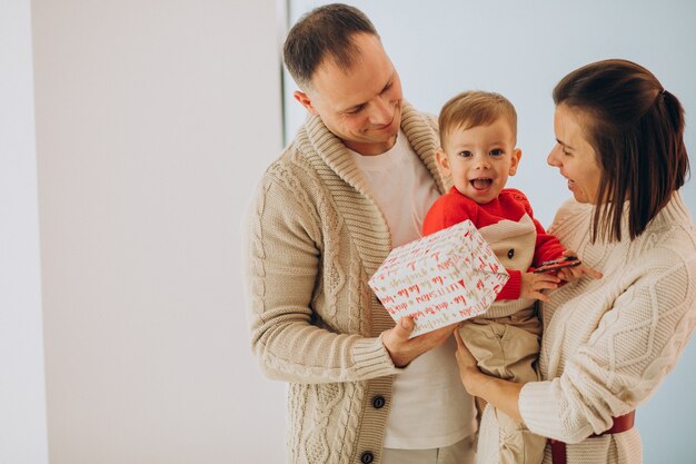 Familia con hijo pequeño en Navidad por árbol de Navidad en casa