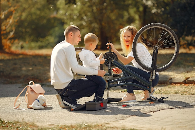 Familia con hijo repare la bicicleta en un parque