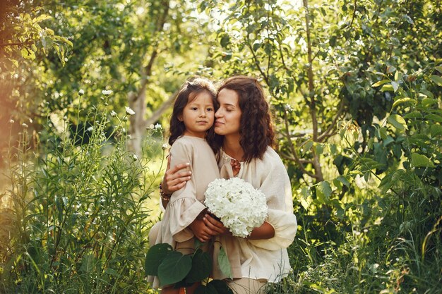 Familia en un jardín de verano. Foto sensual. Pequeña niña bonita. Mujer con ramo.