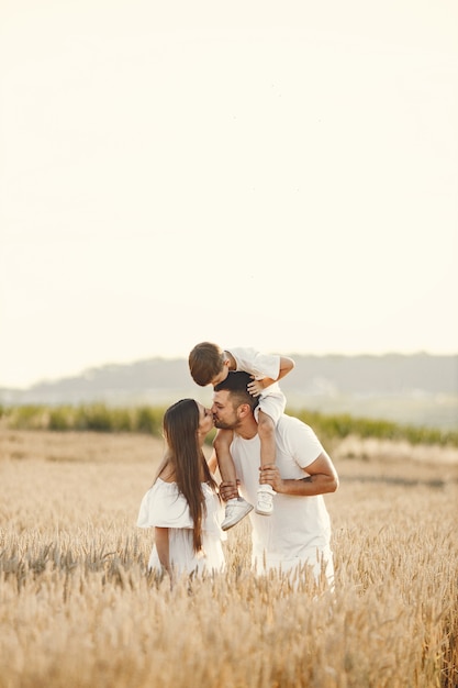 Familia joven en el campo de trigo en un día soleado.