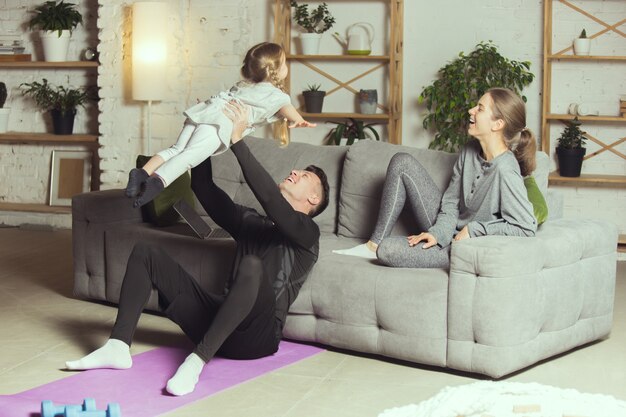 Familia joven descansando después de hacer ejercicio fitness aeróbico yoga en casa estilo de vida deportivo ponerse activo d ...
