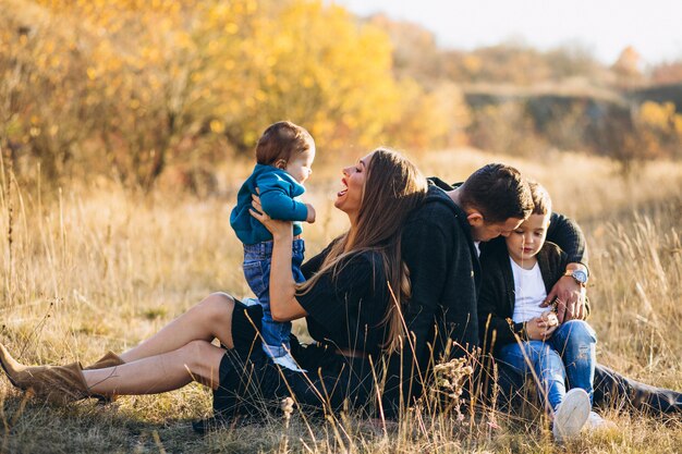 Familia joven con dos hijos juntos sentados en el parque