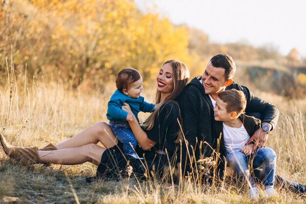 Familia joven con dos hijos juntos sentados en el parque