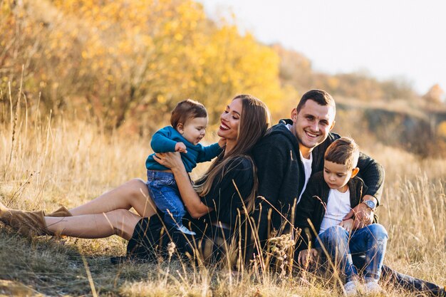 Familia joven con dos hijos juntos sentados en el parque