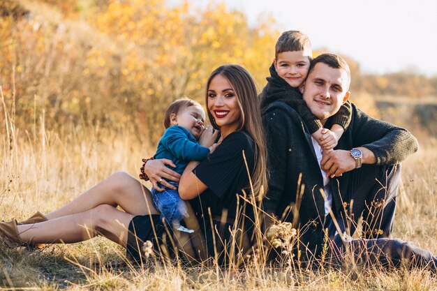 Familia joven con dos hijos juntos sentados en el parque