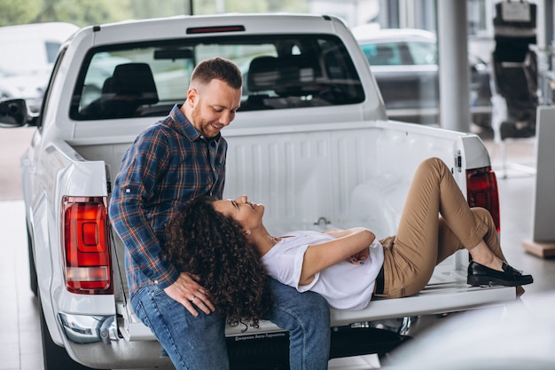 Familia joven eligiendo un automóvil en una sala de exposición de automóviles