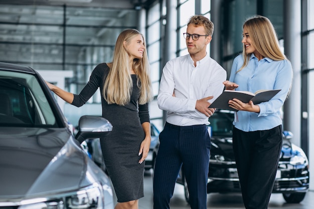 Familia joven eligiendo un automóvil en una sala de exposición de automóviles